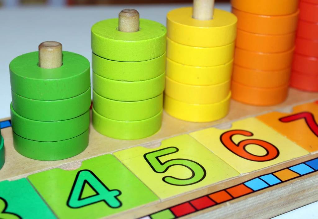 Colorful number cards scattered on a table with toy cars for a preschool counting activity